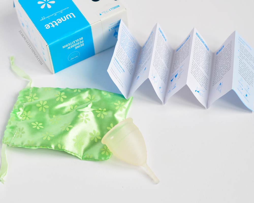 Lunette brand menstrual cup box and contenainance. Lunettes is what I use personally. On the photo, box, instructions, a reusable menstrual cup and a fabric pouch.